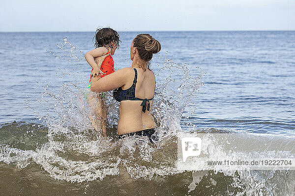 View taken from behind of a mother and daughter playing in the waves of the Pacific Ocean at Kamaole Beach; Maui  Hawaii  United States of America