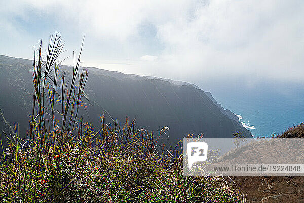 Scenic view of the mountain cliffs of the Napali Coast along the Kalalau Trail on the Hawaiian Island of Kauai looking out to the misty clouds over the blue waters of the Pacific Ocean; Kauai  Hawaii  United States of America