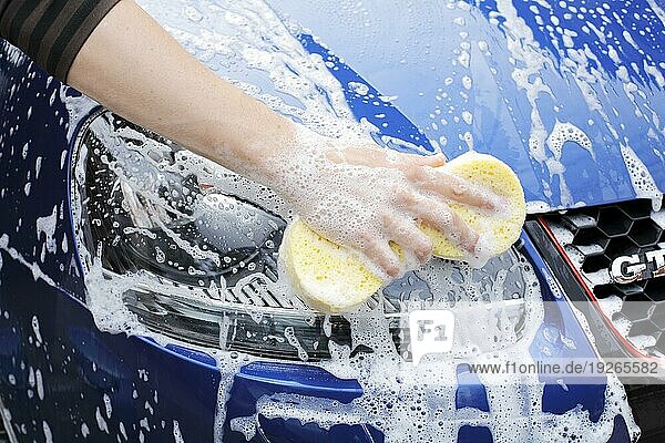 Waschen eines Autoscheinwerfers mit einem Schwamm