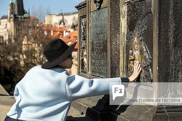 Prag  Tschechische Republik  16. März 2017: Frau berührt die Statue des Nepomuk auf der Karlsbrücke  die Glück bringen soll  Europa