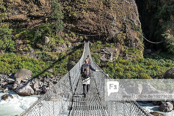 Annapurnaregion 25. Oktober 2014: Wanderer überqueren eine Hängebrücke in der Annapurnaregion