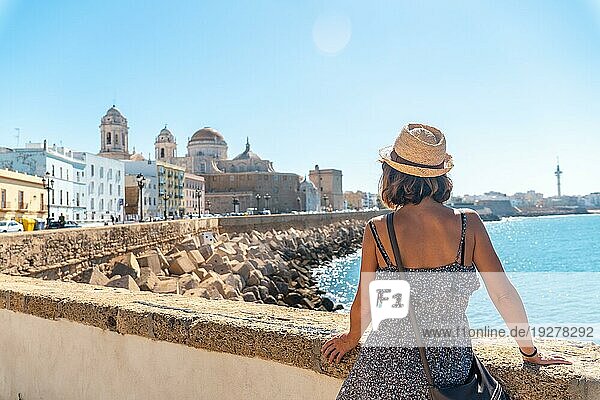 Ein junger Tourist betrachtet die Küste der Stadt Cádiz und die Kathedrale. Andalusien
