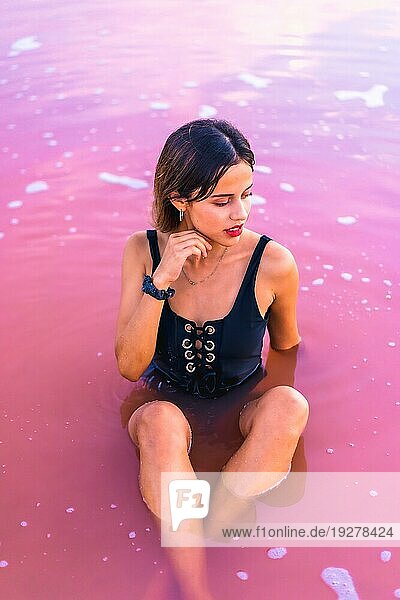 Posing einer jungen brünetten Kaukasierin im Sommerurlaub in der rosa Lagune von Torrevieja  die im Wasser sitzt  Alicante. Spanien