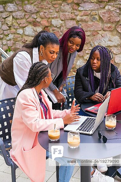 Junge Geschäftsfrauen schwarzer Ethnie. In einer Teamwork Sitzung  in einer Cafeteria mit Computern und Notizen