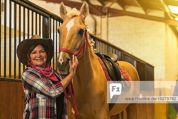 Porträt einer erwachsenen Frau im Pferdestall mit einem braunen Pferd  gekleidet in südamerikanischer Tracht