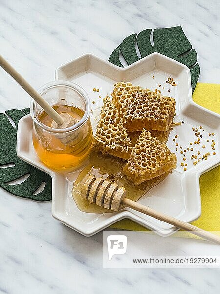 Honiglöffel Honigwabe mit Bienenpollen weißes Tablett Marmorkulisse