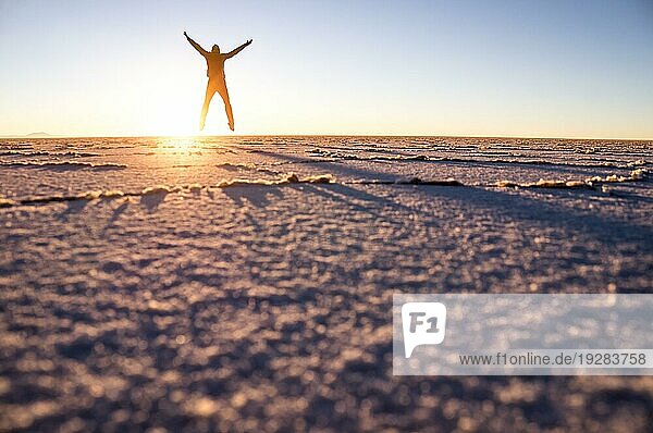 Salar de Uyuni: Männlicher Tourist springt bei Sonnenaufgang über den Salzsee und erzeugt ein schönes Muster