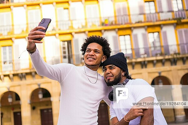 Lifestyle  zwei schwarze Latino Freunde machen ein schönes Selfie auf der Straße. Junge mit Afrohaar und Junge mit Hut und Kopfhörer