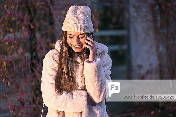 Junge hübsche kaukasische Brünette  die im Winter in der Stadt spazieren geht und einen rosa Wollpullover trägt