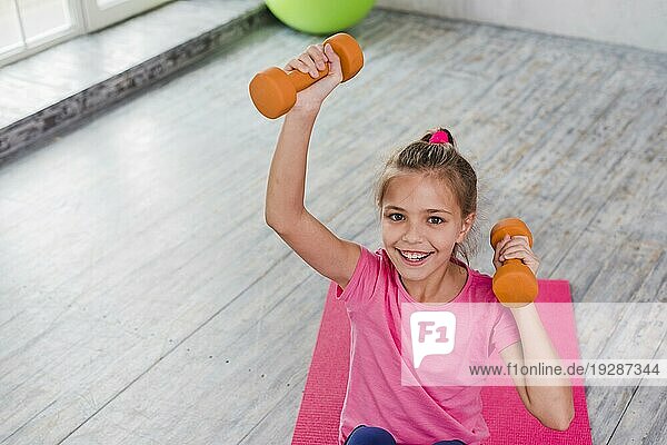 Portrait lächelndes Mädchen beim Training mit orangefarbener Hantel