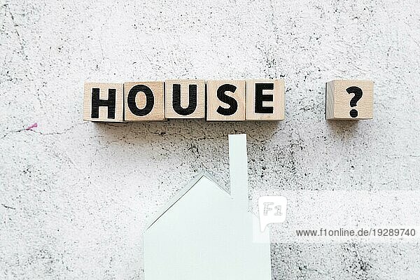 Angeordnetes Haus Textblöcke mit Fragezeichen Papier Haus Modell gegen konkrete Hintergrund