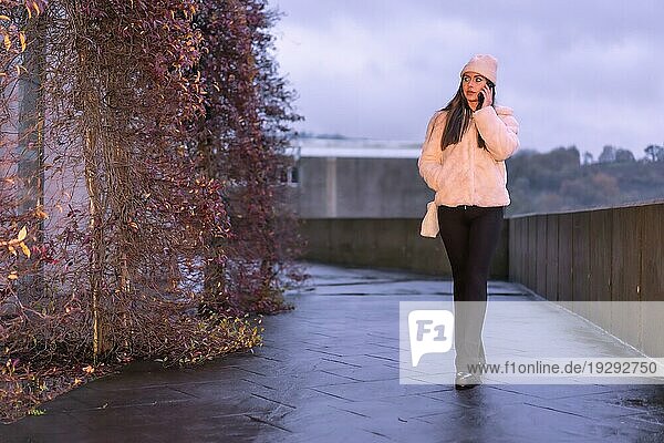 Junge hübsche kaukasische Brünette  die im Winter in der Stadt spazieren geht und einen rosa Wollpullover trägt