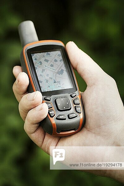 Ein Mann hält einen GPSempfänger in der Hand. Handgehaltene GPS Geräte werden vor allem in der Outdoor Freizeitindustrie für Spaziergänge und Wanderungen verwendet