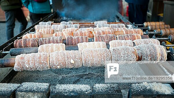 Tschechische süße Spezialität Trdelnik auf Holzstangen über einer Feuerstelle in Prag