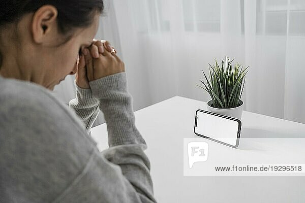 Frau betet zu Hause mit Smartphone