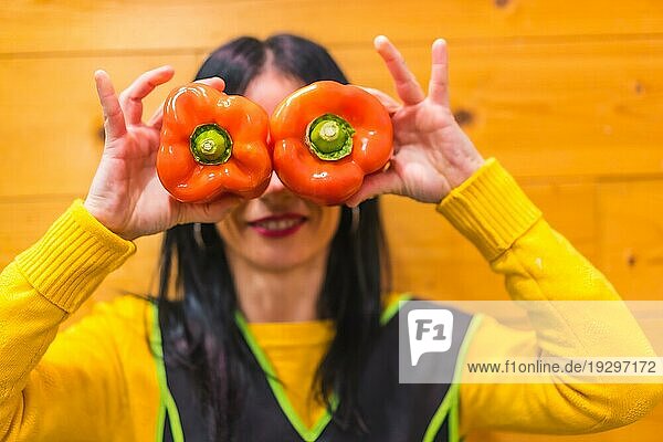 Ein brünettes kaukasisches Obstmädchen  das in einem Gemüseladen arbeitet  hat Spaß an roten Paprika in der Hand