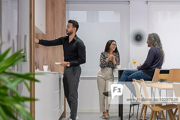 Drei Mitarbeiter unterhalten sich entspannt in der Küche eines Co Working Spaces während einer Kaffeepause