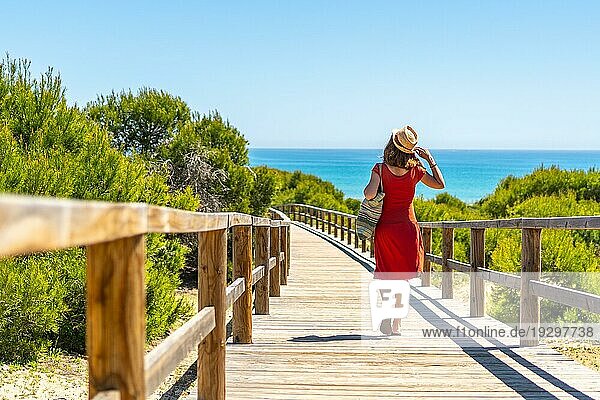 Ein junges Mädchen auf dem Holzweg zum Playa Moncayo in Guardamar del Segura bei Torrevieja  Alicante. Gemeinschaft von Valencia. Spanien  Urlaub am Mittelmeer