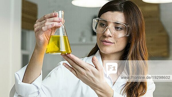 Wissenschaftlerin mit Schutzbrille hält Reagenzglas