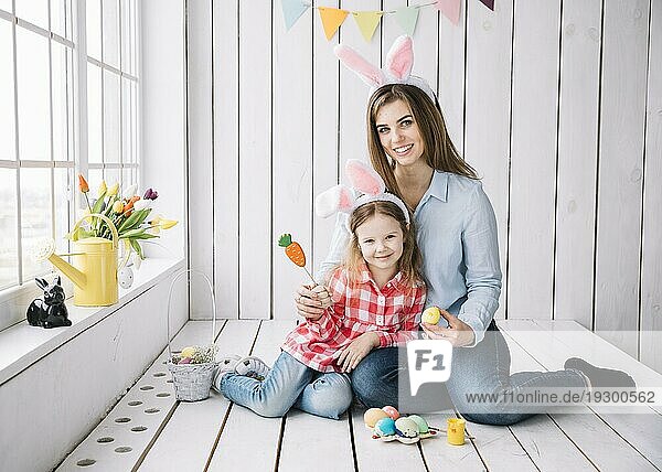 Nettes Mädchen Mutter Hasenohren sitzen mit Ostereiern