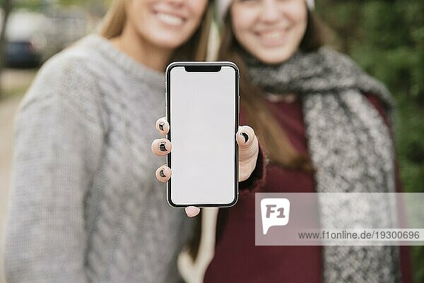 Nahaufnahme von zwei lächelnden Frauen  die ein Telefon in der Hand halten