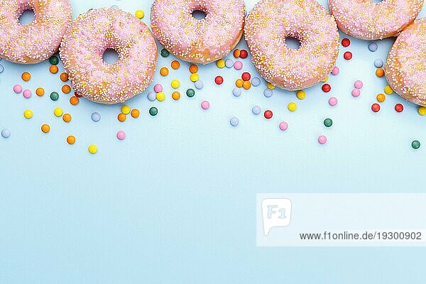 Rosa Donuts und Süßigkeiten auf blauem Hintergrund  Copy Space Flat Lay