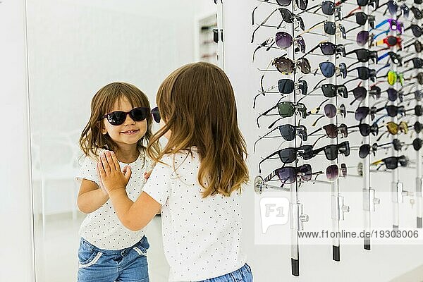Kind mit Sonnenbrille im Spiegel