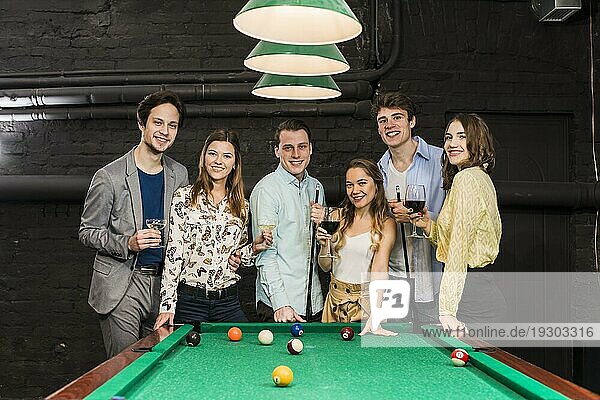 Gruppe glücklich lächelnder Freunde mit Getränken am Snookertisch