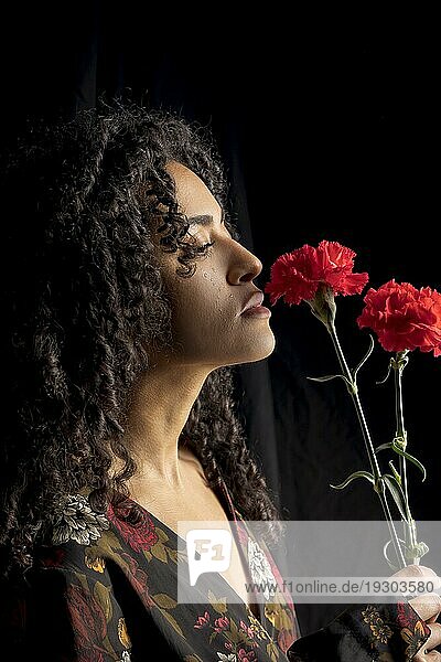 Zarte ethnische Frau mit Blumen Dunkelheit