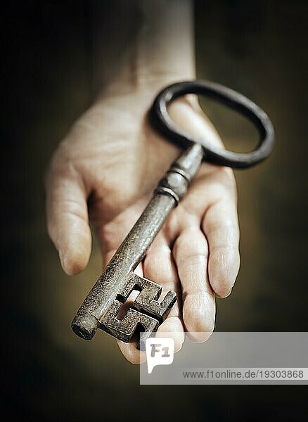 Mann hält großen antiken Schlüssel in der Hand. Sehr kurze Tiefenschärfe