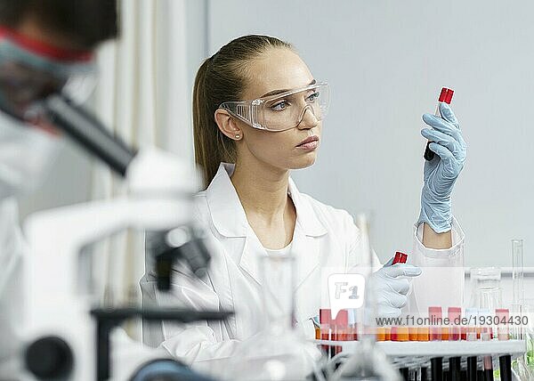 Weibliche Forscherin Labor mit Reagenzgläsern Schutzbrille männlicher Kollege