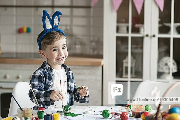 Porträt glücklicher kleiner Junge beim Bemalen von Ostereiern