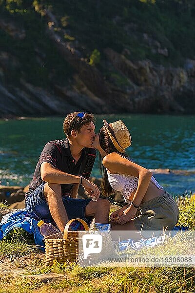 Romantische Szene eines Paares  das sich beim Picknick in den Bergen am Meer küsst und die Hitze genießt  Lebensstil im Sommer