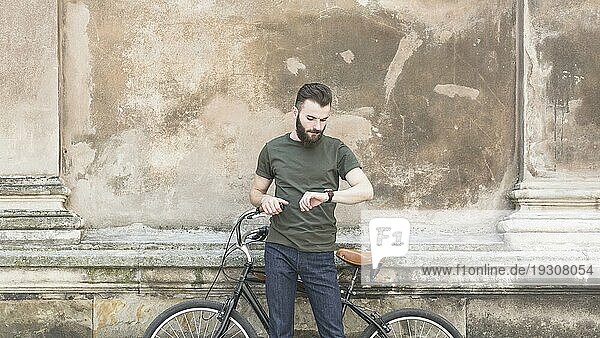 Mann mit seinem Fahrrad auf der Suche nach einer Uhr am Handgelenk