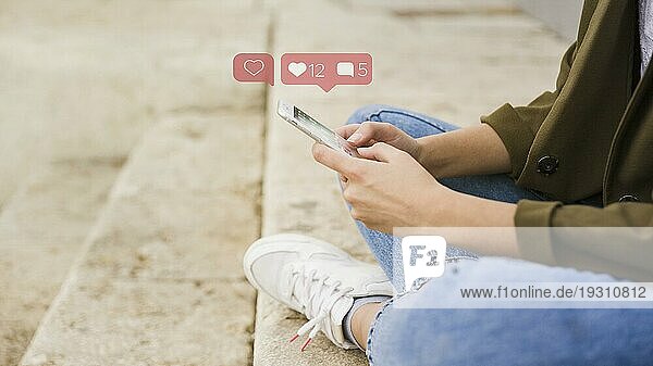 Nahaufnahme einer Frau  die auf einer Treppe sitzt und eine mobile Social Media App benutzt