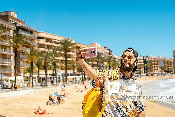 Ein junger Tourist mit dem Telefon am Playa del Cura in der Küstenstadt Torrevieja  Alicante  Valencianische Gemeinschaft. Spanien  Mittelmeer