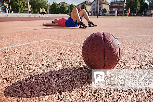 Basketballspieler am Boden mit Ball im Vordergrund