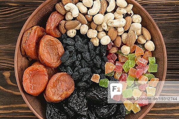 Erhöhte Ansicht Aprikose getrocknete Früchte schwarze Rosinen Nüsse Schüssel Holzoberfläche