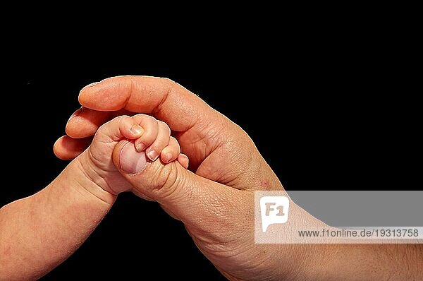 Neugeborenes vertraut der Hand eines Erwachsenen
