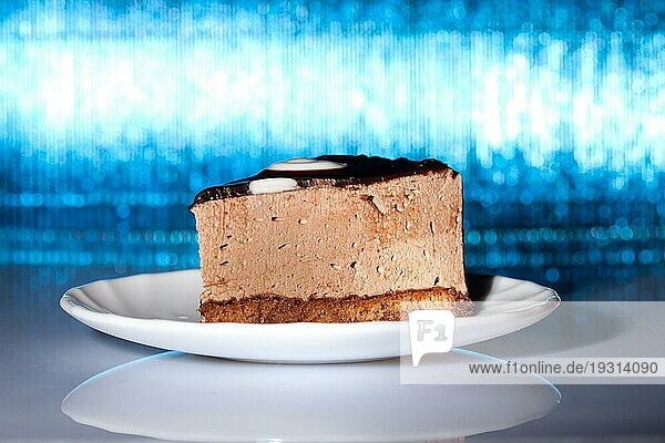 Leckerer Schokoladenkuchen auf leuchtend blauem Hintergrund. Unscharfer Fokus