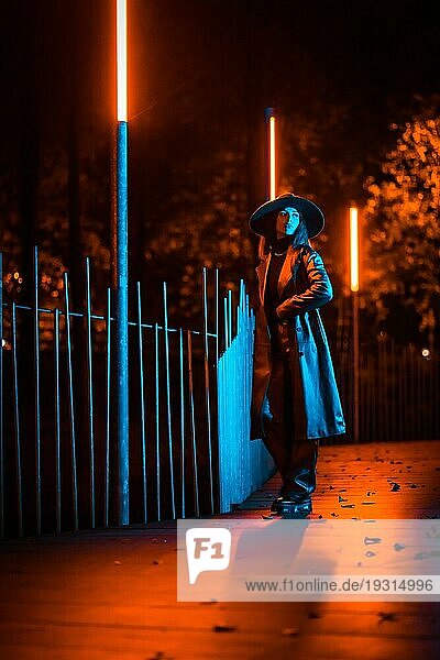 Mädchen mit Hut geht nachts in einem Park spazieren  nachdenklich und genießt die Ruhe ohne Menschen  blaues Licht