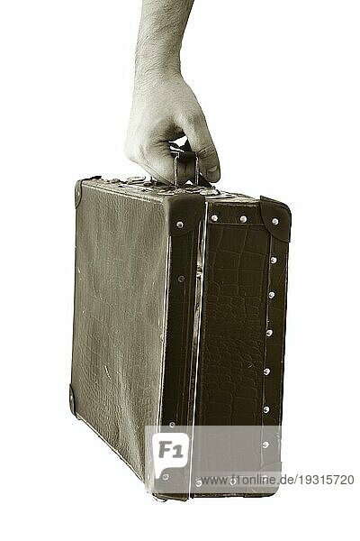 Sepia getöntes Foto einer Hand  die einen alten Koffer hält. Kurze Schärfentiefe  die Schärfe liegt in der Hand