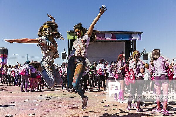 Aufgeregte junge Frauen springen in die Luft und feiern das Holifest