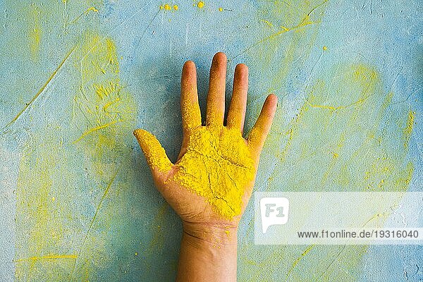 Gelbes Pulver Person s Palme gegen gemalt chaotisch Wand mit Farbe