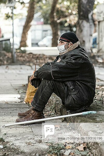 Seitenansicht Obdachloser Mann im Freien mit Stock medizinische Maske