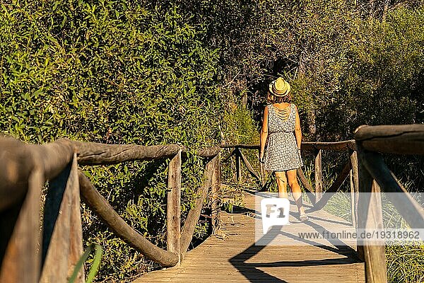 Ein junger Tourist geht auf einem Holzsteg im Doñana Naturpark in Huelva spazieren. Andalusien