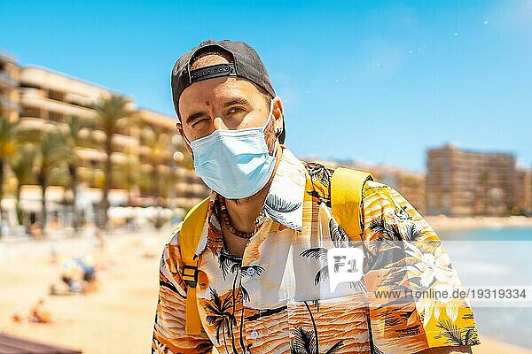 Ein junger Mann mit einer chirurgischen Touristenmaske am Strand von Cura in der Küstenstadt Torrevieja  Alicante  Valencianische Gemeinschaft. Spanien  Mittelmeer