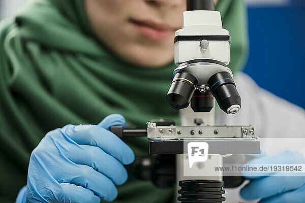 Wissenschaftlerin mit Hidschab bei der Arbeit im Labor mit Mikroskop