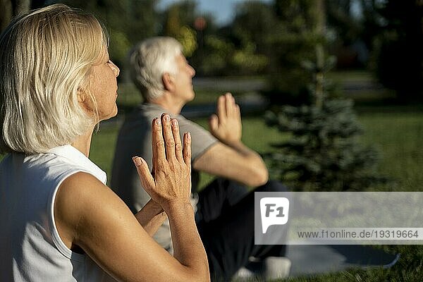 Seitenansicht älteres Paar übt Yoga im Freien