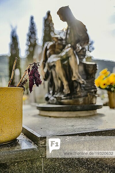 Blumentopf mit verwelkter Blume auf einem Grab vor einer religiösen Marienfigur mit Jesus in den Armen im Gegenlicht  Bari Sardo  Ogliastra  Sardinien  Italien  Europa